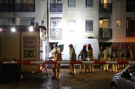 Brandweer helpt bewoners naar beneden na brand in portiek