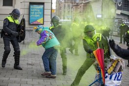 Oudere vrouw gooit poeder op agent bij Corona-rellen in Amsterdam