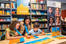 Stadsdeelvoorzitter Tanja Jadnanansing (Amsterdam-Zuidoost) en boer Ayoub laten boek signeren door jonge Amsterdamse schrijvers