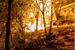 Persfotografen ontdekken brand en redden persoon uit brandend tentenkamp langs A10 in Amsterdam