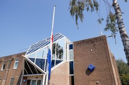 Bloemen en vlaggen halfstok voor overleden motoragent
