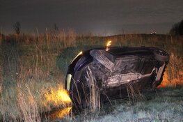 Auto vliegt uit de bocht en belandt op zijkant in greppel