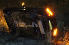 Auto vliegt uit de bocht en belandt op zijkant in greppel