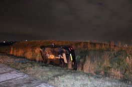 Auto vliegt uit de bocht en belandt op zijkant in greppel